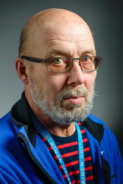 Muotokuva keski-ikäisestä silmälasipäisestä miehestä, joka katsoo kameraan.